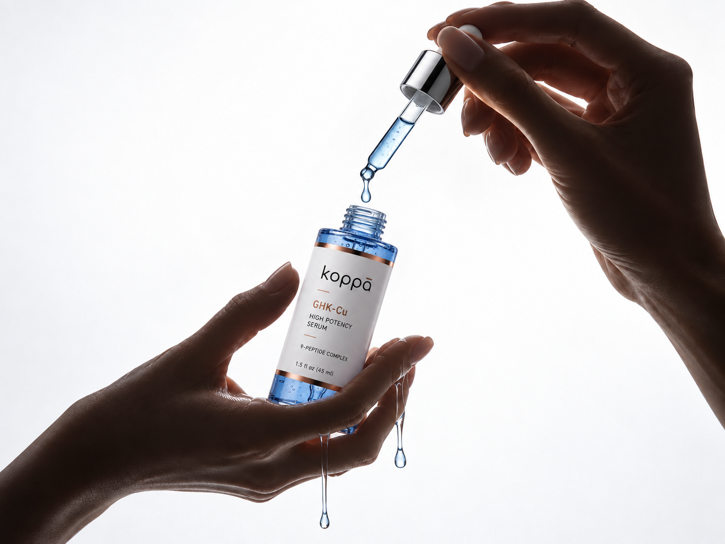 Backlit hands holding a cobalt blue serum bottle and pipette