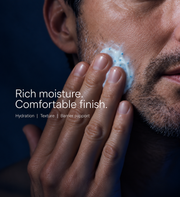 Man massaging copper peptide cream into his cheek with blue capsules visible