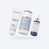 Koppā GHK-Cu Trio — balm stick, 2% serum and capsule cream on a soft porcelain background