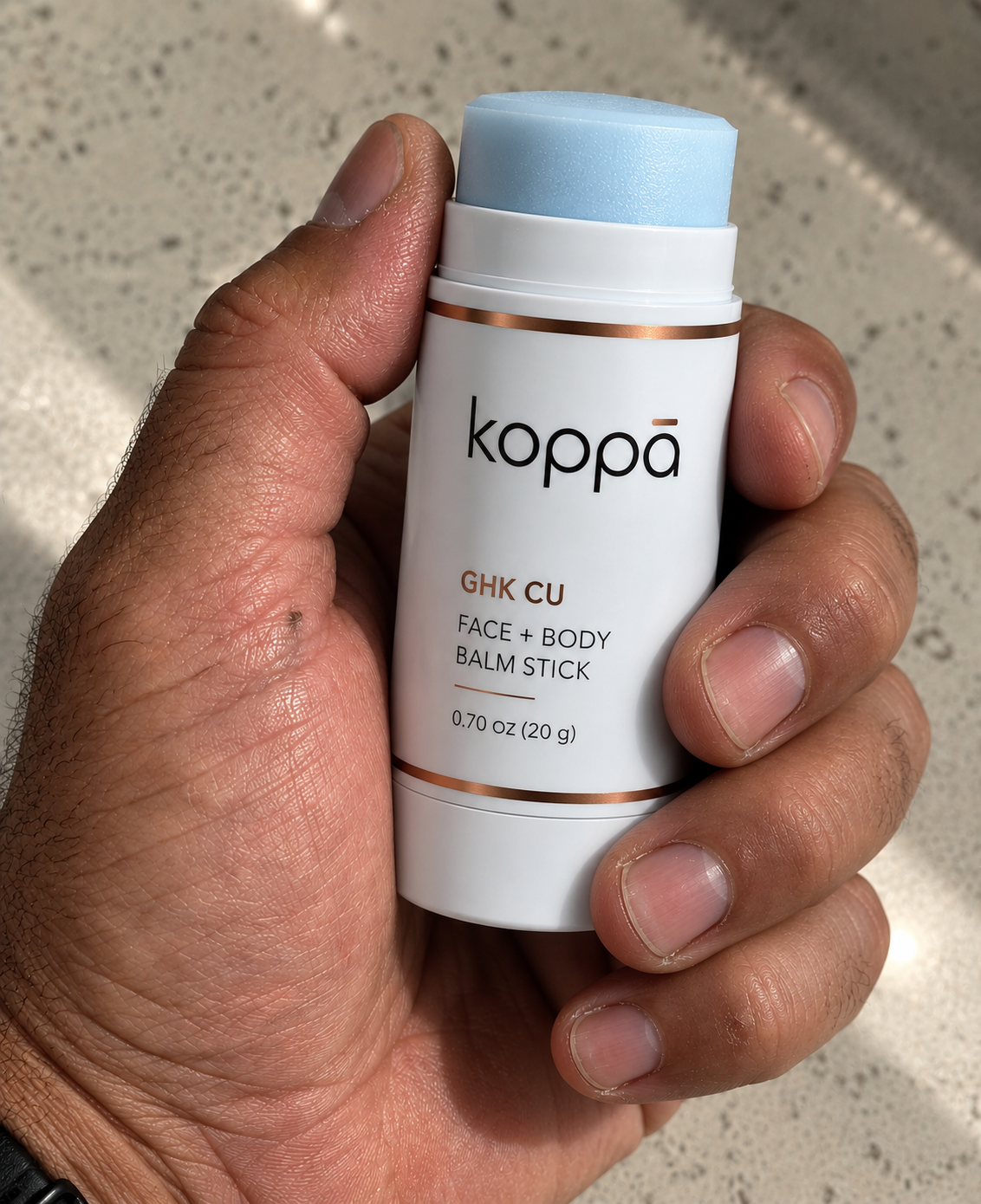 Koppā GHK-Cu balm stick held in a hand