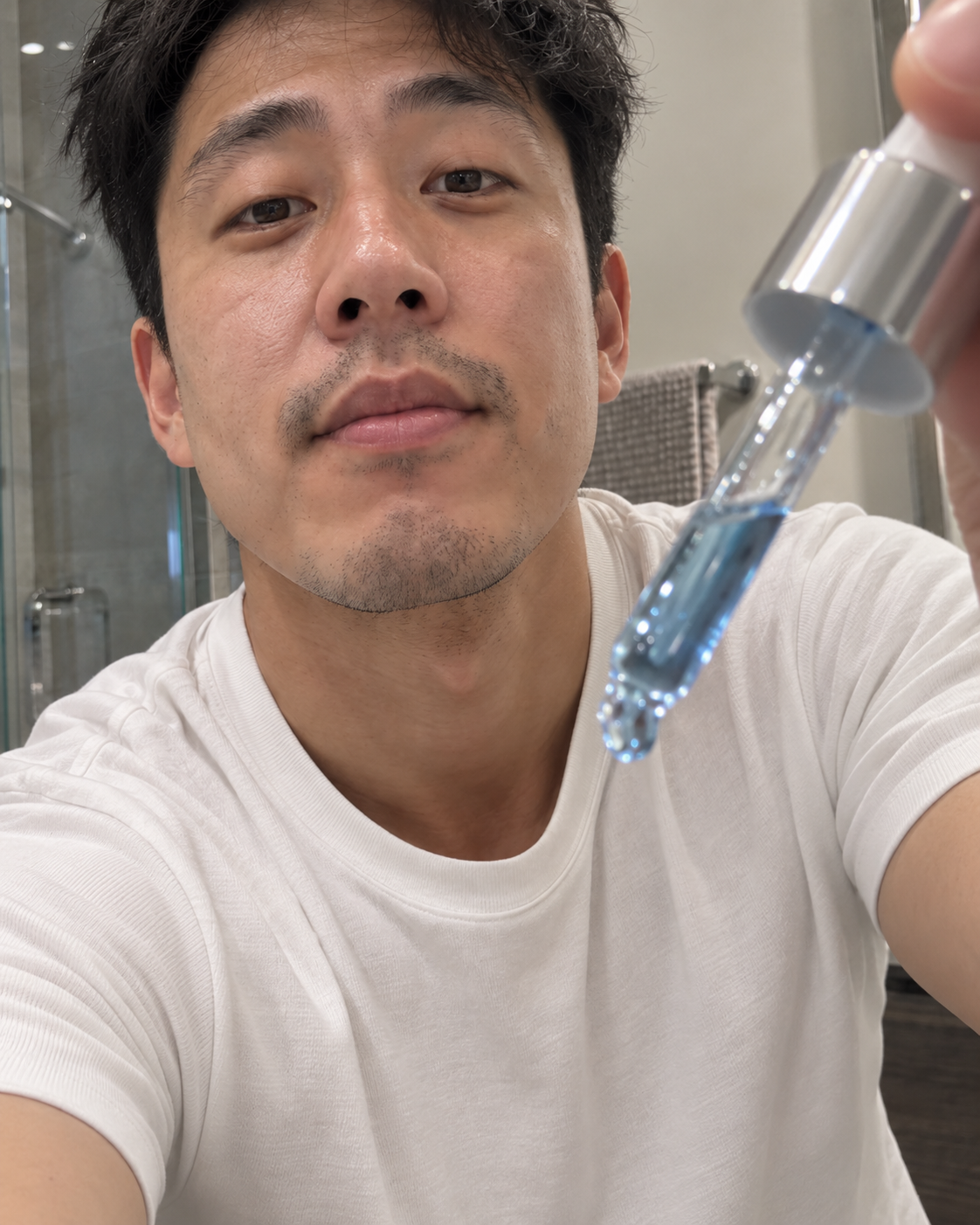 Man holding a dropper of Koppā copper peptide serum