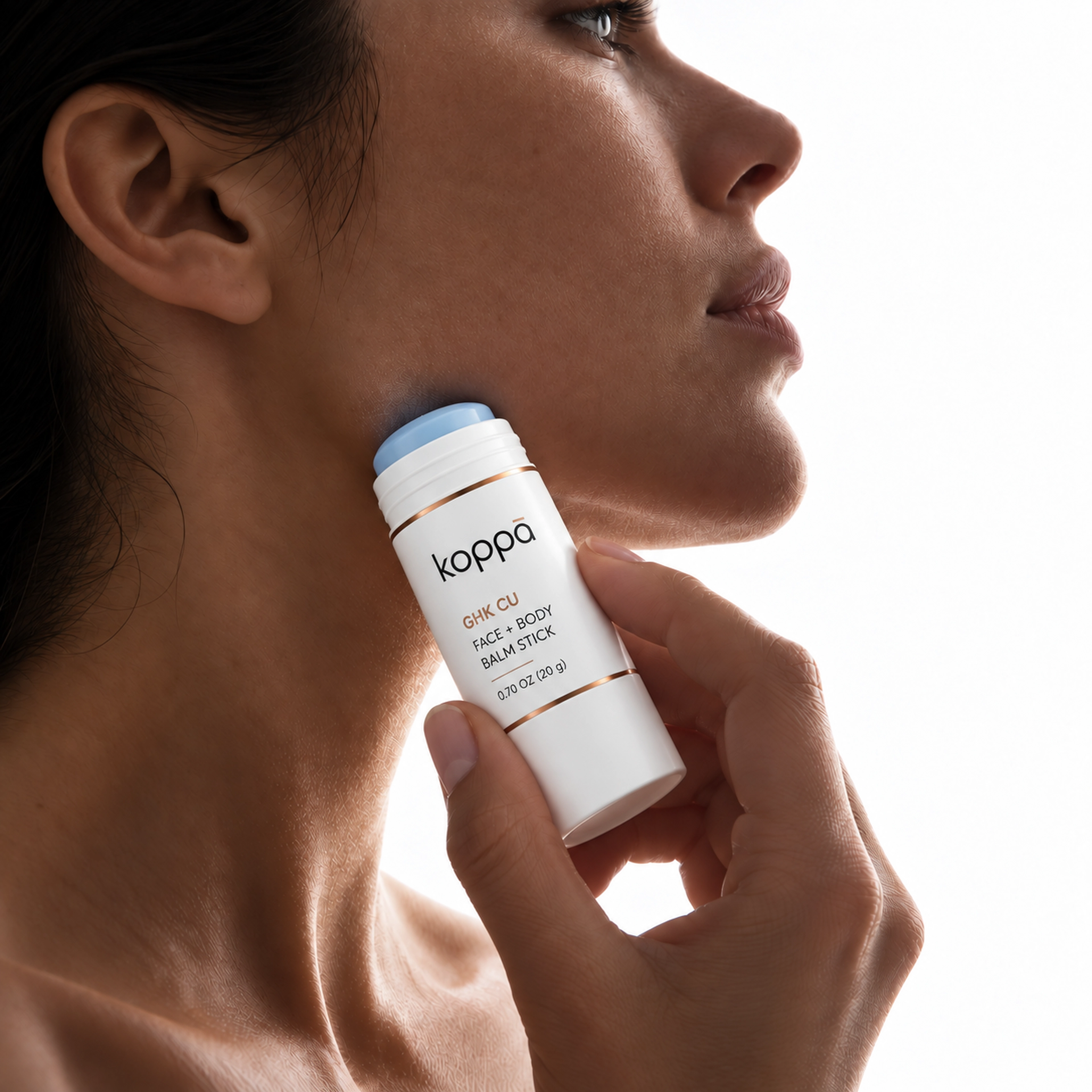 Koppā balm stick being swiped along the side of the jaw in soft editorial light